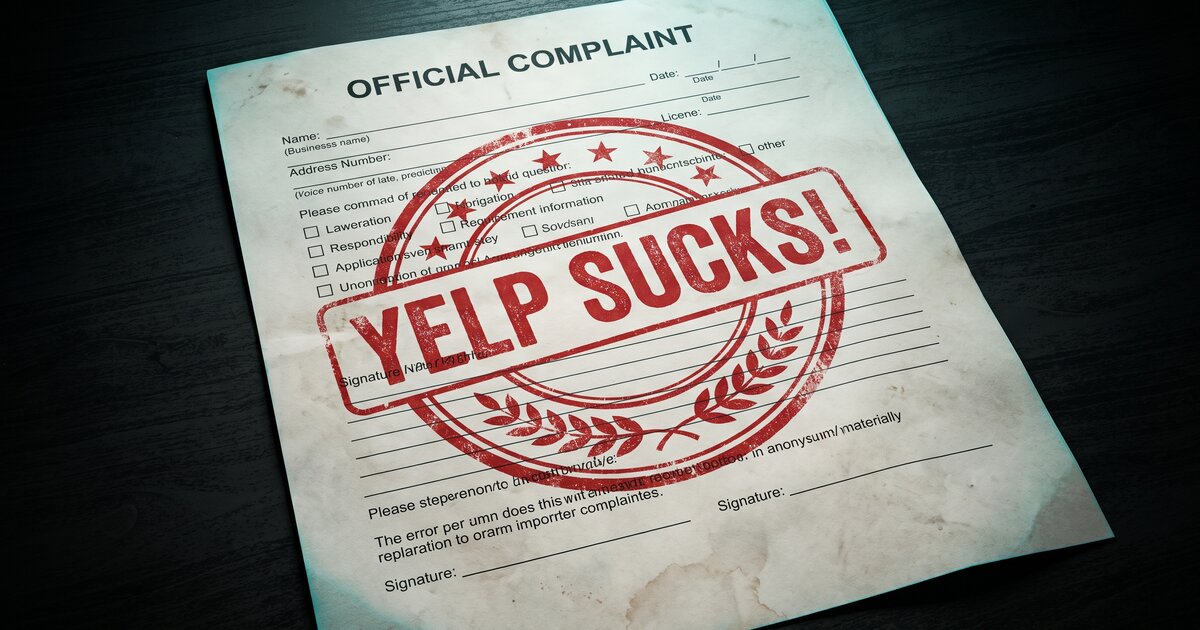 A stamped Official Complaint form on a dark desk with a large red YELP SUCKS! seal across it.